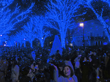 青色の光で包まれた空間に人工雪が舞った