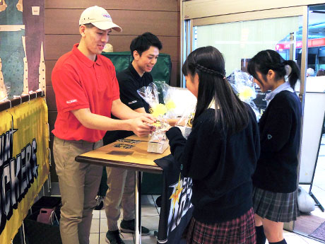 KKDのユニホーム姿でドーナツなどを手渡したベンドラメ礼生選手（左）と伊藤駿選手（左から2番目）
