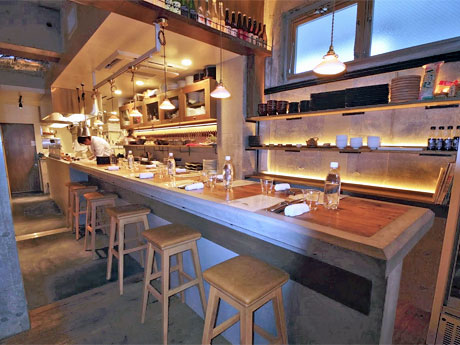 暖色の照明や木目の家具を配置したシックな内装の店内