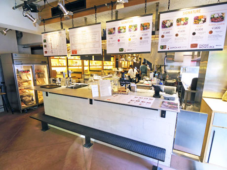 サラダを盛る工程が見られるオープンキッチンが特徴の店内