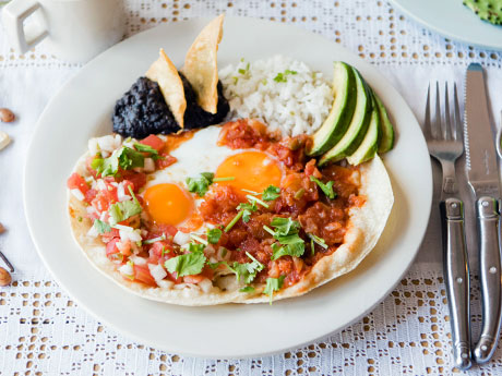 トルティーヤにサルサと目玉焼きをのせる「ウェボス・ランチェロス」を中心にするプレート