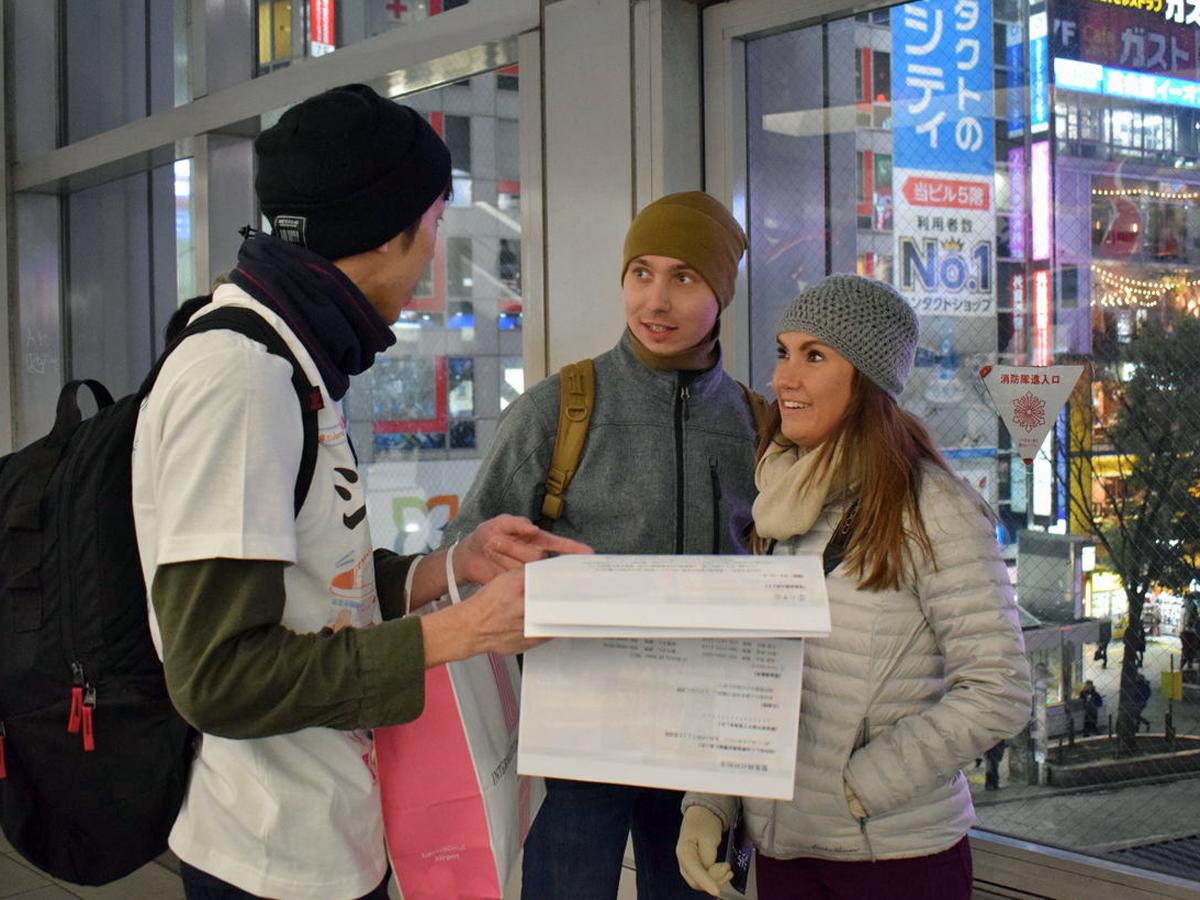 渋谷駅前（スクランブル）交差点を解説するガイドの野村昇吾さん（左）とKalachikさん
夫婦（右）