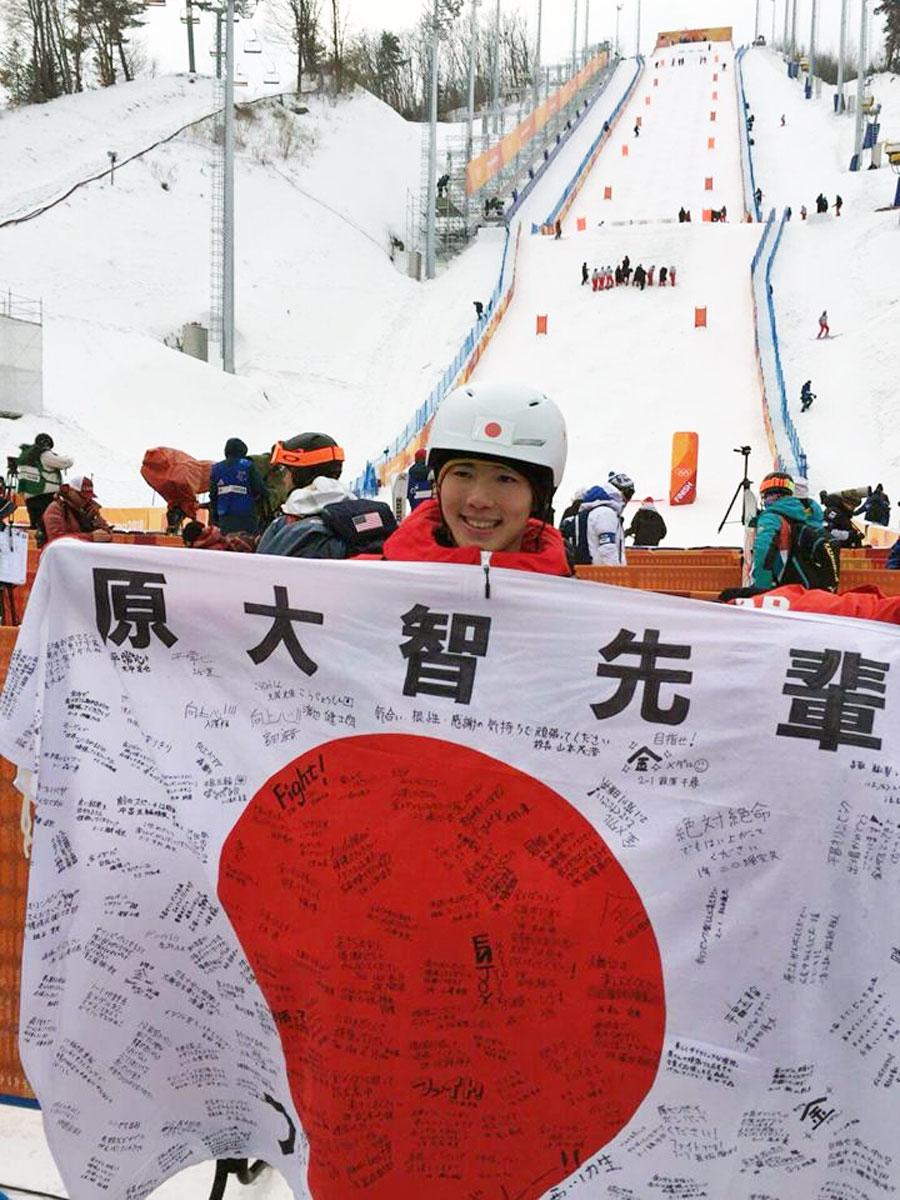 母校・広尾中在校生たちの寄せ書きが書かれた国旗を持つ原大智選手（広尾中学校フェイスブックより）