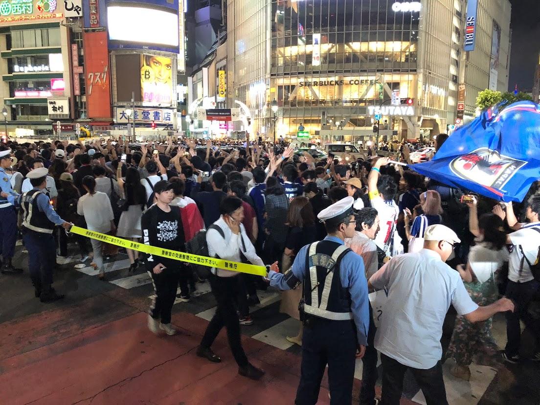 ハイタッチを交わしながら交差点を横断するサポーターら