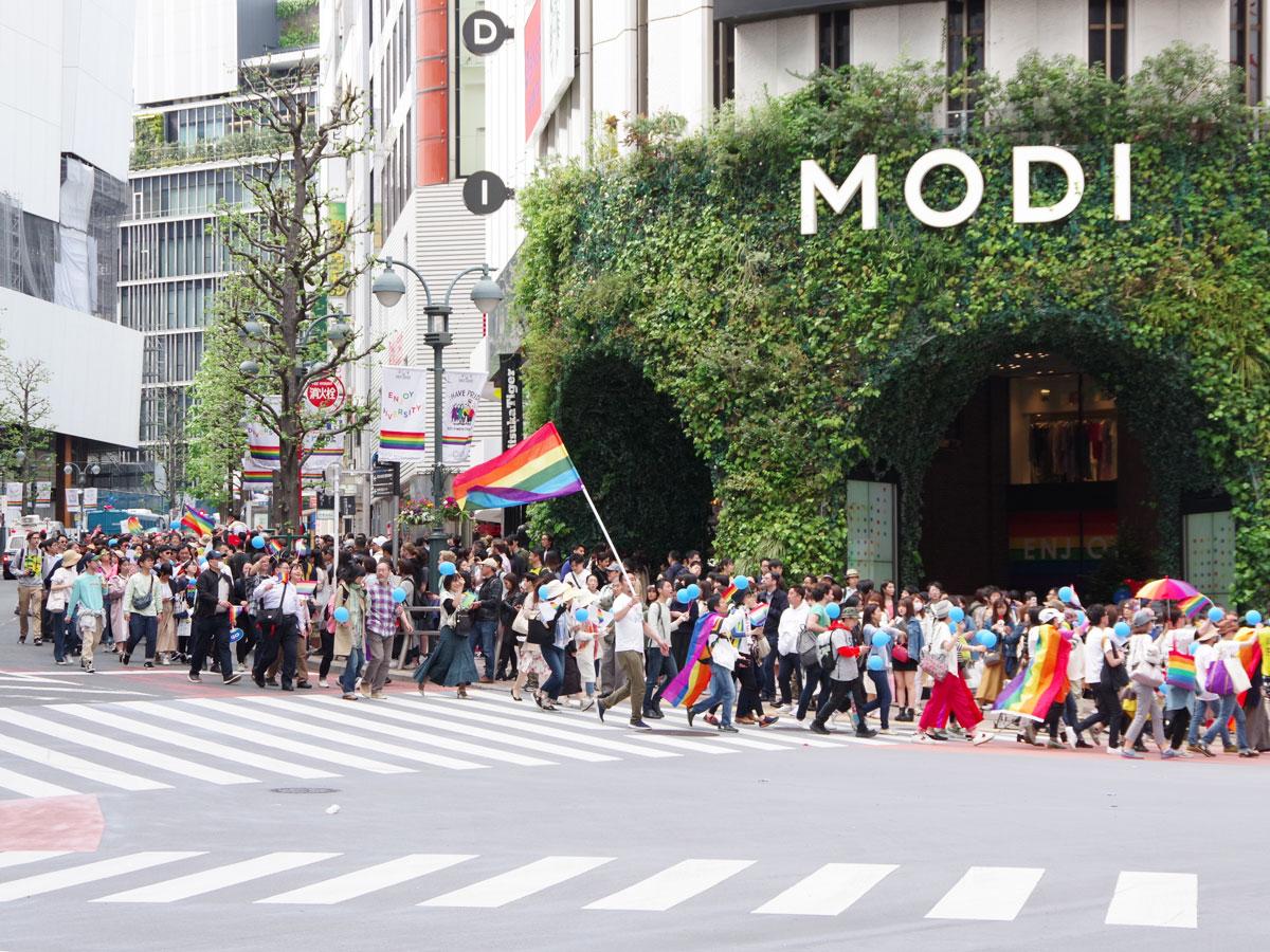 虹色の旗を持った人やカラフルなアイテムを身に付けた約1万人の人たちが街中をパレードした