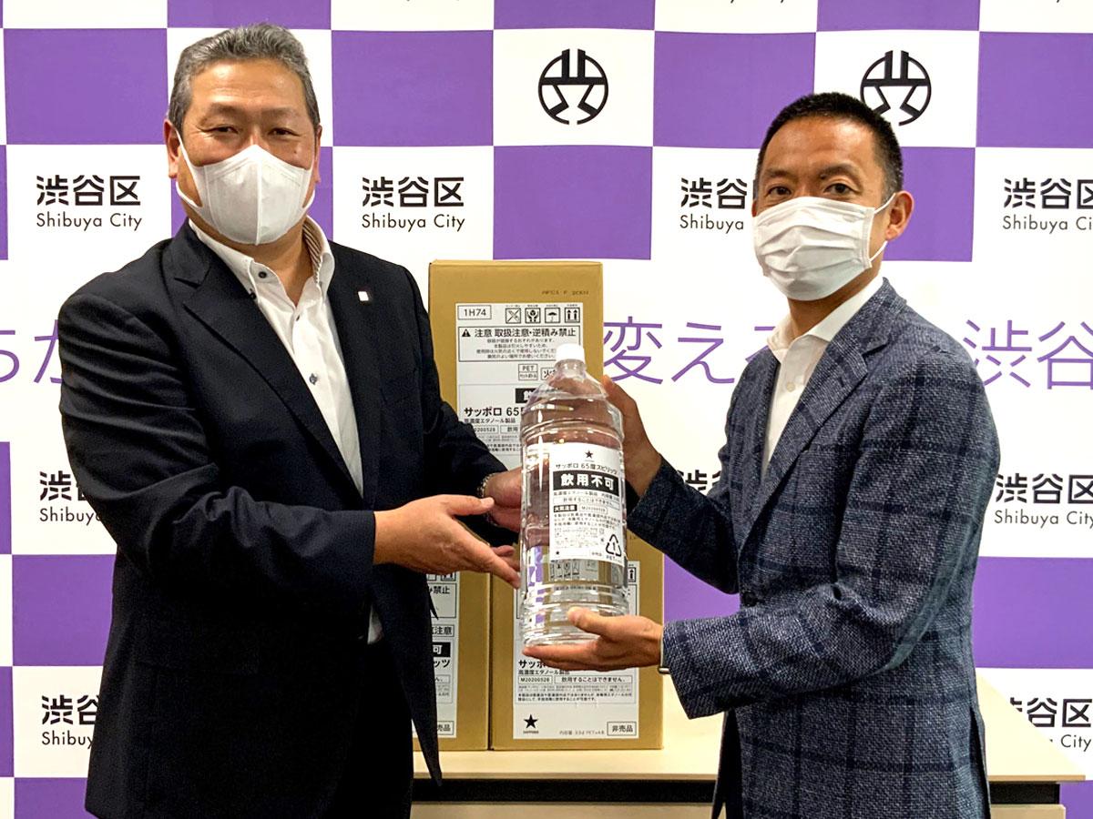 サッポロビール執行役員広域法人営業本部長の大西恭弘さんから高濃度エタノールを受け取る長谷部健渋谷区長（右）