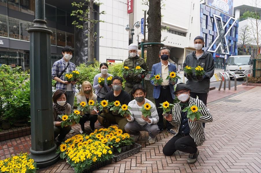 渋谷公園通りの花壇に黄色い花を植える庭園デザイナー石原和幸さん（写真右）ら
