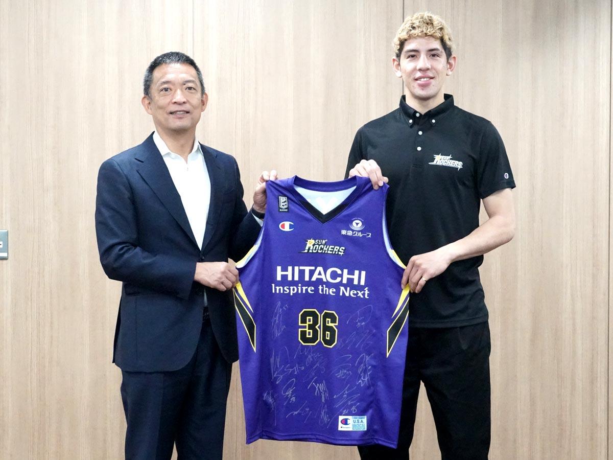 渋谷区の花・ハナショブ色のユニホームを手渡したベンドラメ礼生選手（右）