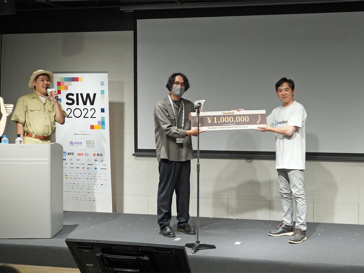 グランプリを受賞した寺田忠勝さん（中央）とロケトーン・プロデューサーの安彦剛志さん（右）。左はMCを務めたロケトーン公式アンバサダーで声優のモアイ岩下さん