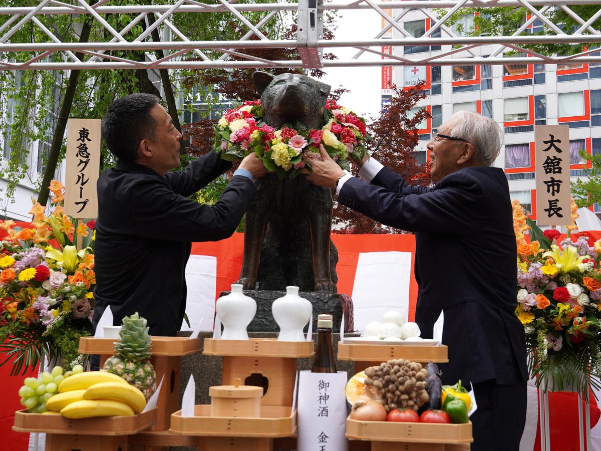 ハチ公像に花輪をかける長谷部区長（左）と星野会長（右）