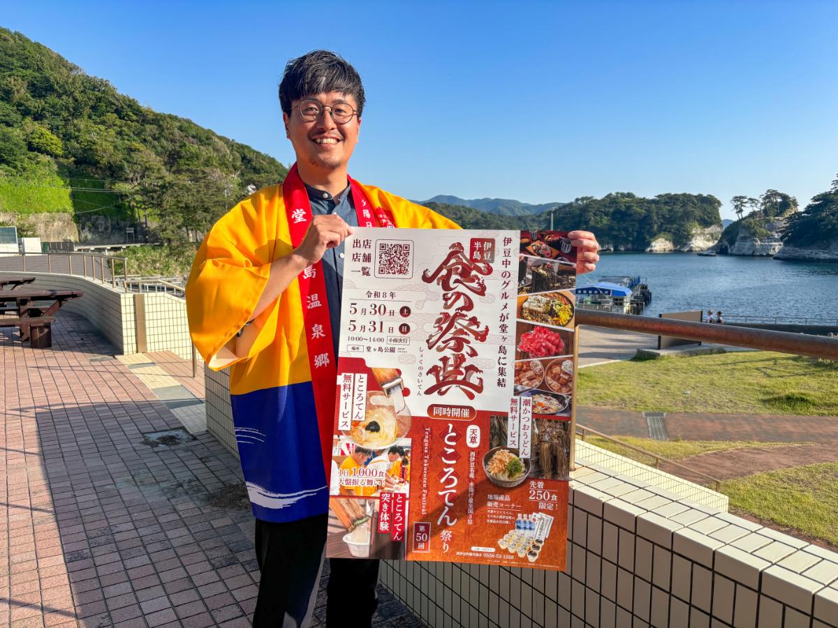 「伊豆半島食の祭典」のポスターを掲げる西伊豆町観光協会の小塩秀次さん