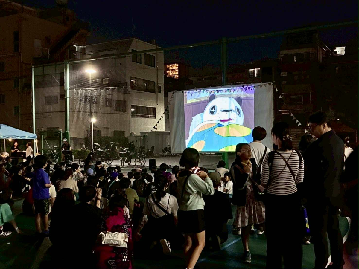 中和小学校の校庭で上映された映画「パンダコパンダ」を見入る親子連れや地域住民