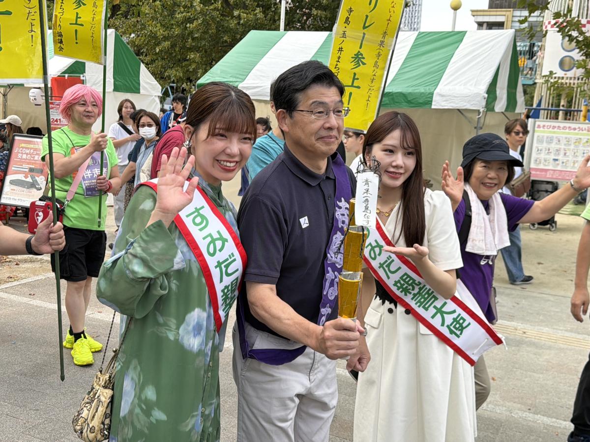 寺島なすのトーチを手にする山本亨区長と、すみだ親善大使ら
