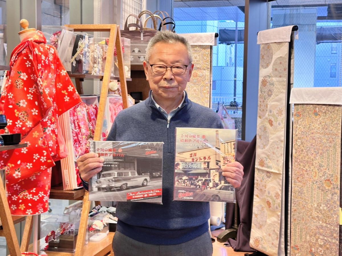 立川商工会議所商業部会長の中里晋さんと賞品のアルバムシリーズ