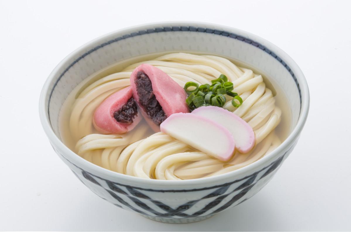 白い麺に赤色のあんもちやかまぼこを載せる「さぬきの年明けうどん」（写真提供＝全国ご当地うどんサミット in さぬき実行委員会）