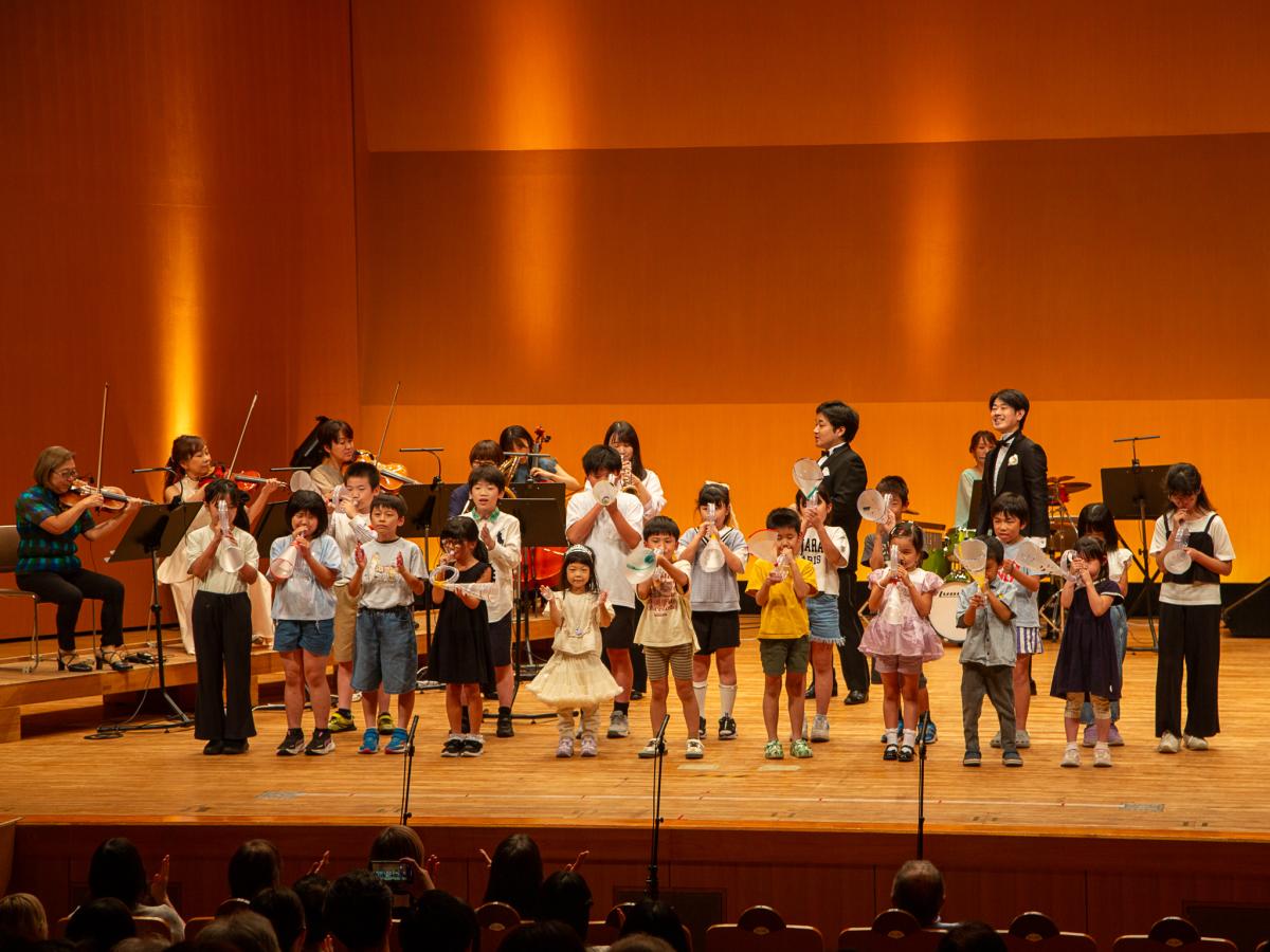 楽団と手作り楽器を持った子どもたち19人が共演した