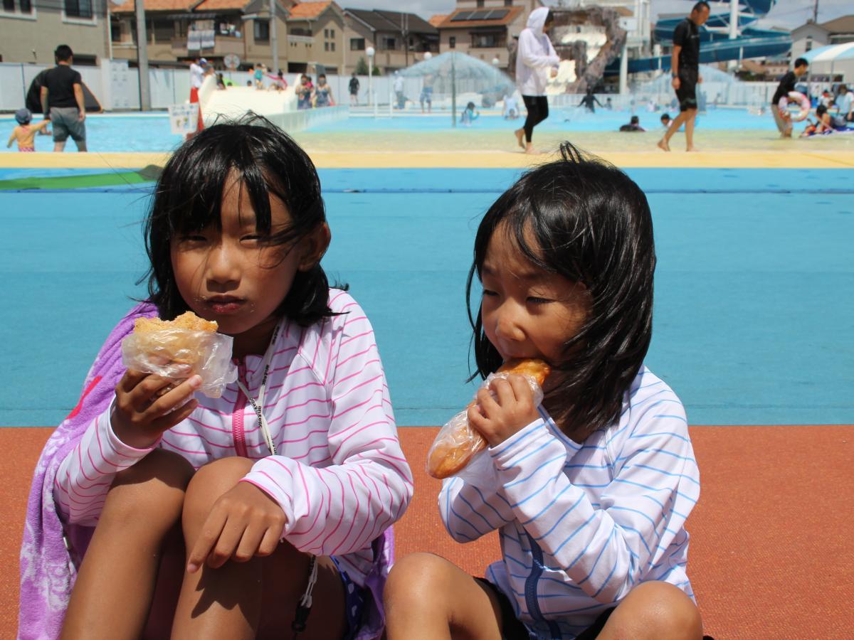 市民プールで揚げパンを頬張る子ども