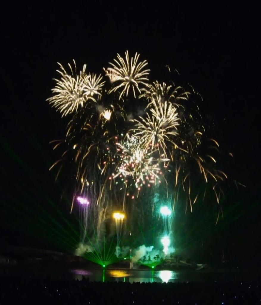 花火とレーザー光線が浜辺と夜空に浮かぶ