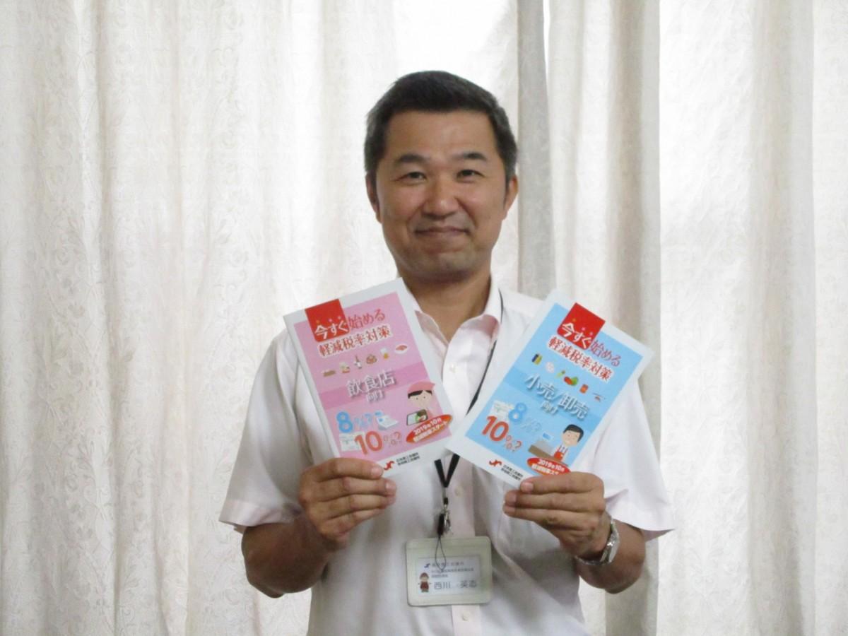 軽減税率対策の冊子を持ちPRする西川さん