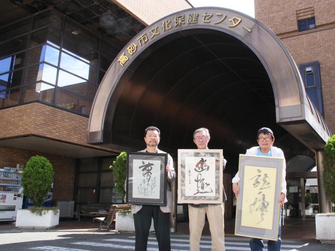 作品を手に来場を呼び掛ける小嶋さん(左)、田中さん(中)、大道さん(右)