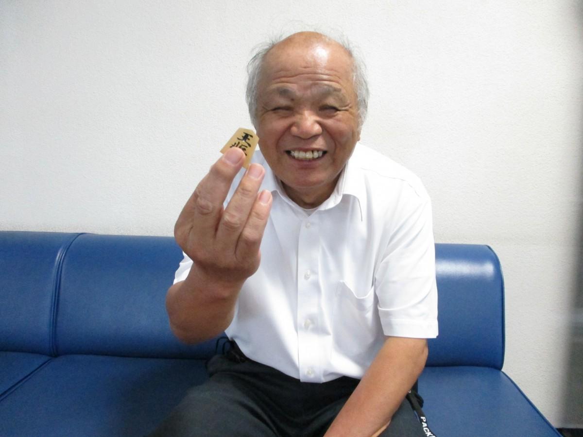 駒を手に笑顔の好田隆さん