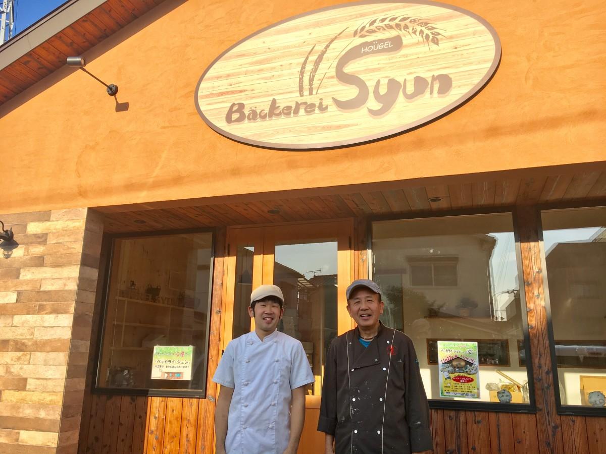 新しいお店の前で笑顔の代表橋本芳秋さん(右)とシェフ橋本隼輔さん(左)