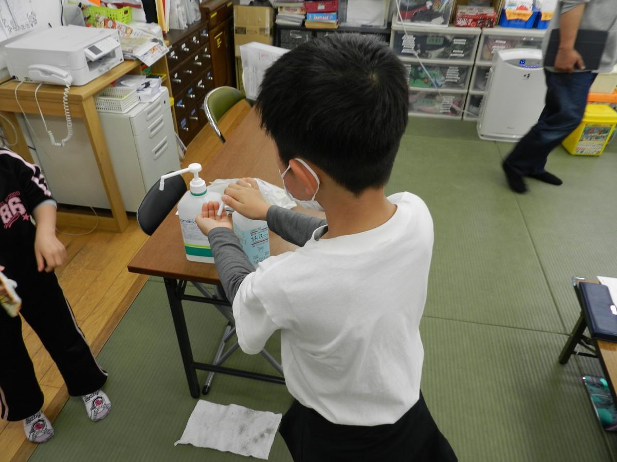 手をアルコール消毒する児童