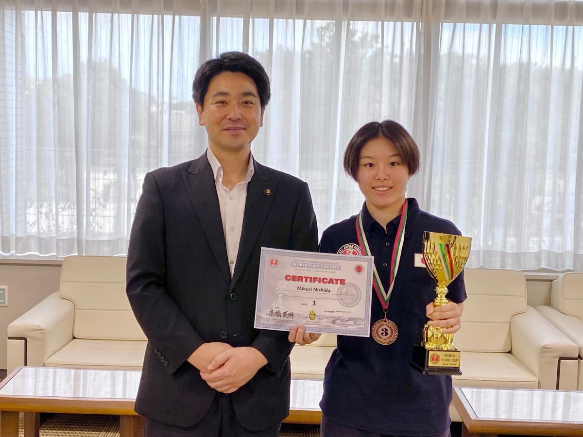 トロフィーを片手に小山市長(左)と記念撮影する西田さん(右)
