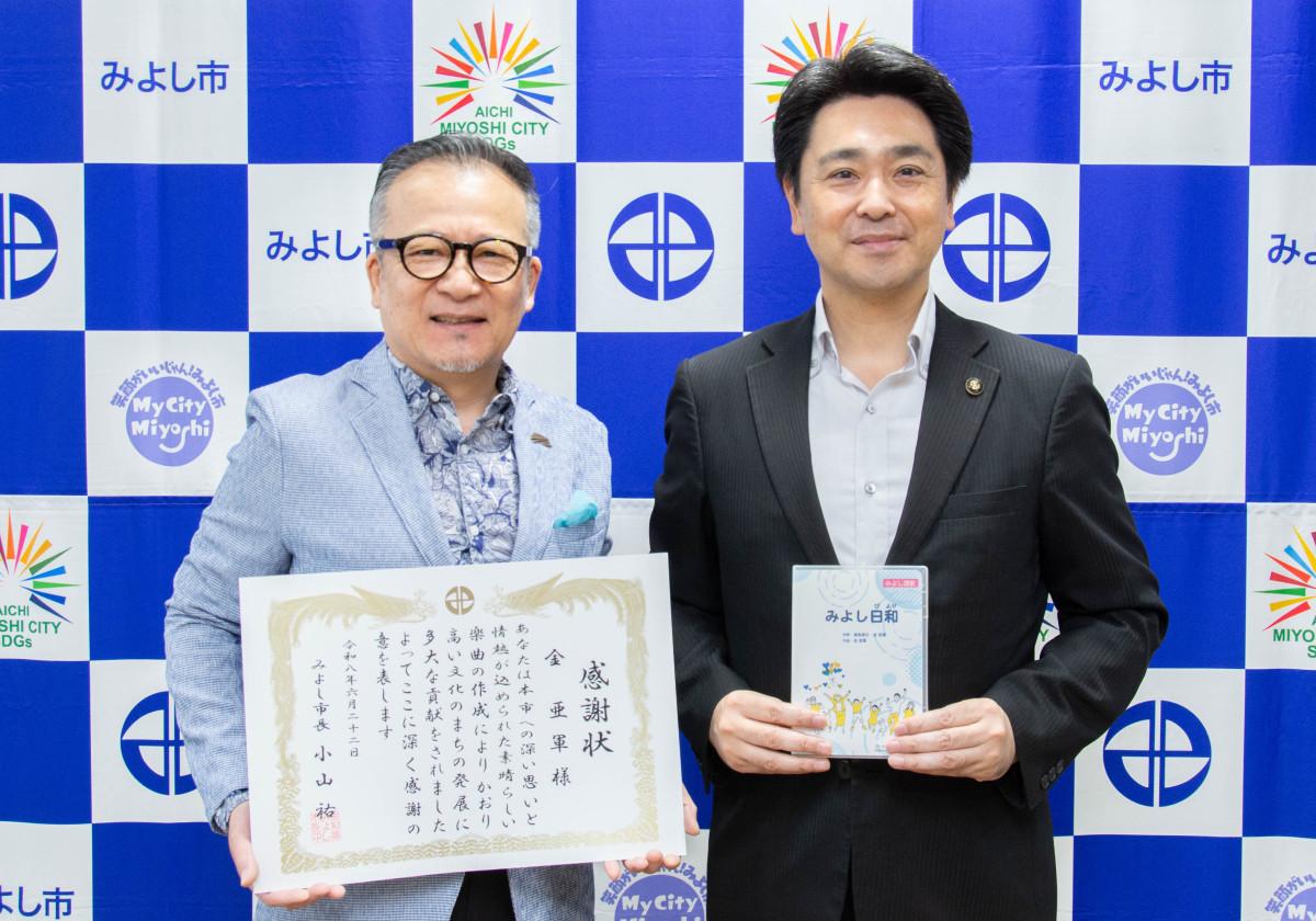 感謝状を手にする金さん（左）と、手渡されたCDを手にする小山市長（右）。写真提供：みよし市