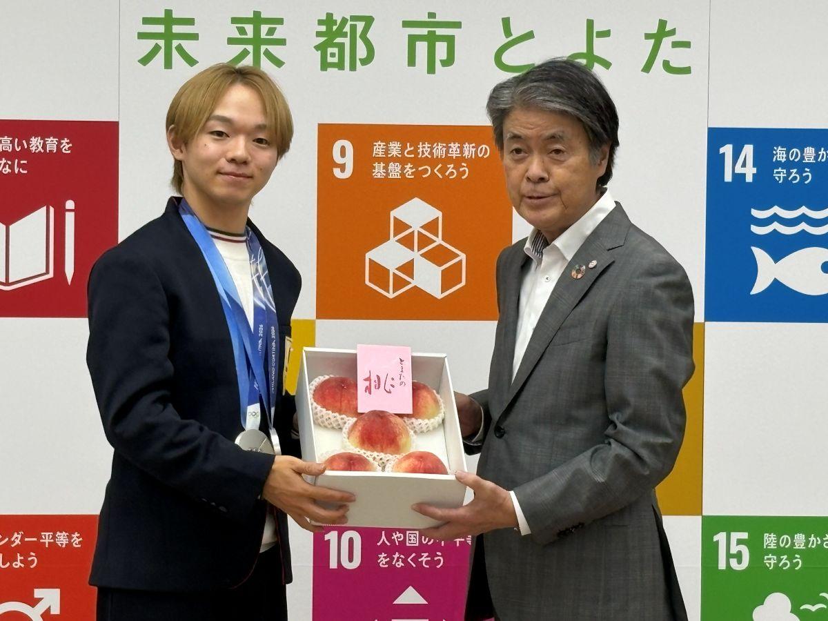 豊田市の特産品の桃を贈呈された鍵山選手（左）と太田市長（右）