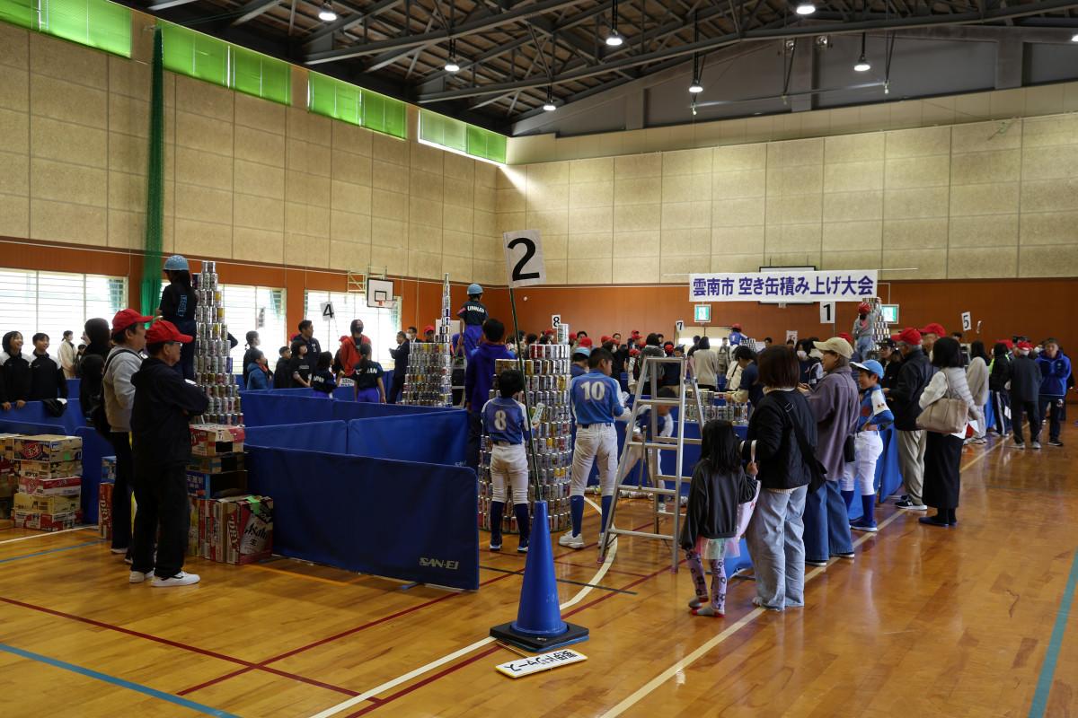 会場の体育館で空き缶を積み上げる参加者たち