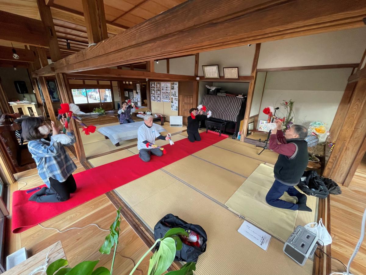 「みんなのお家」の大広間で銭太鼓を体験する参加者たち