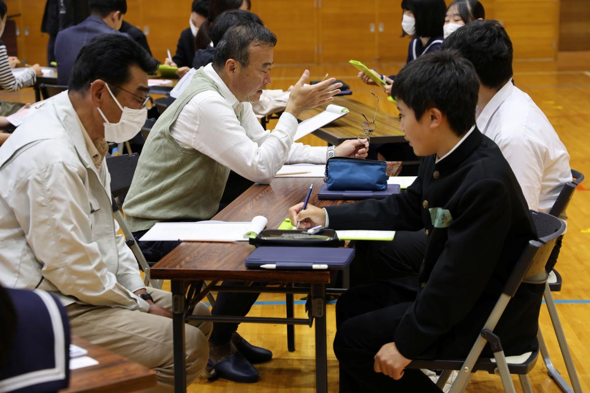 中学3年生相手に熱心に話す前田弘人さん（左から2人目）