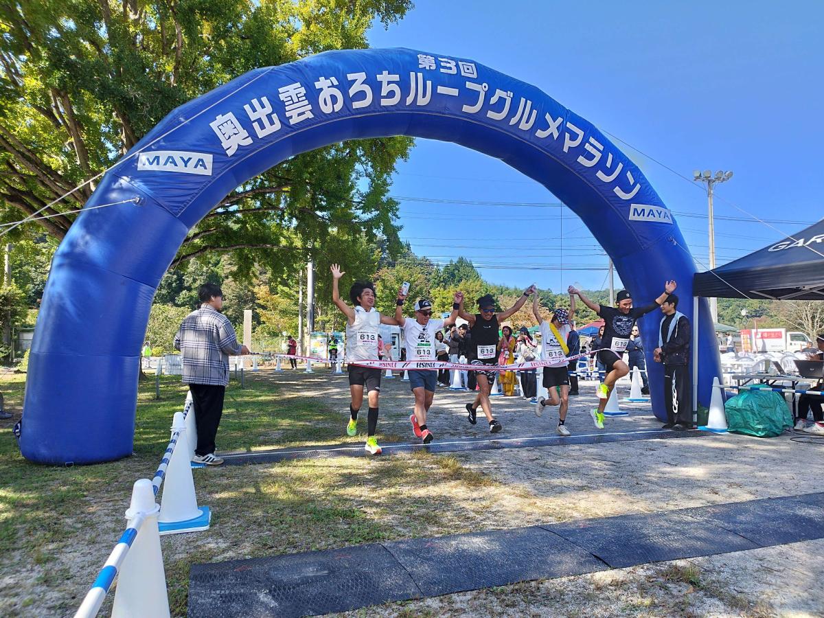 仲間と手をつなぎ、笑顔でゴールするランナー