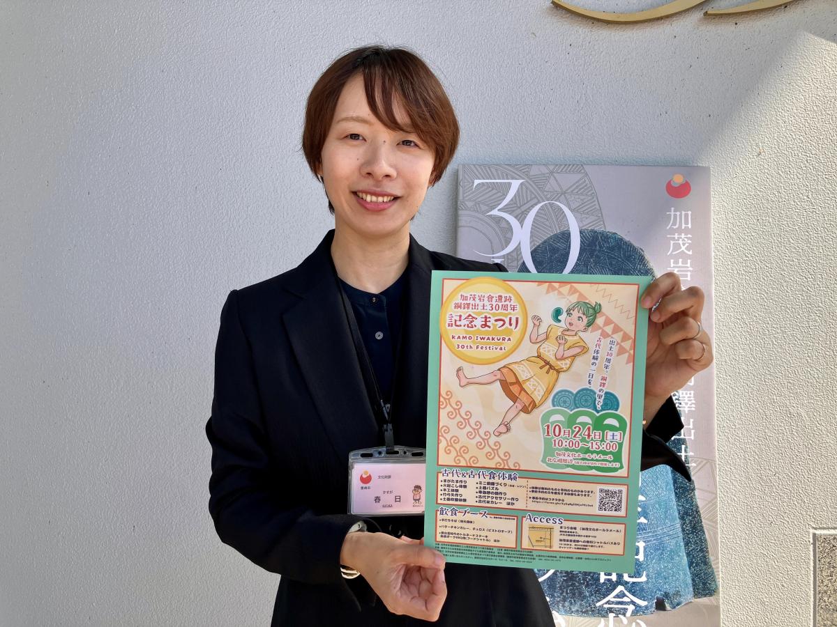 イベントのチラシを掲げ、来場を呼びかける春日さん