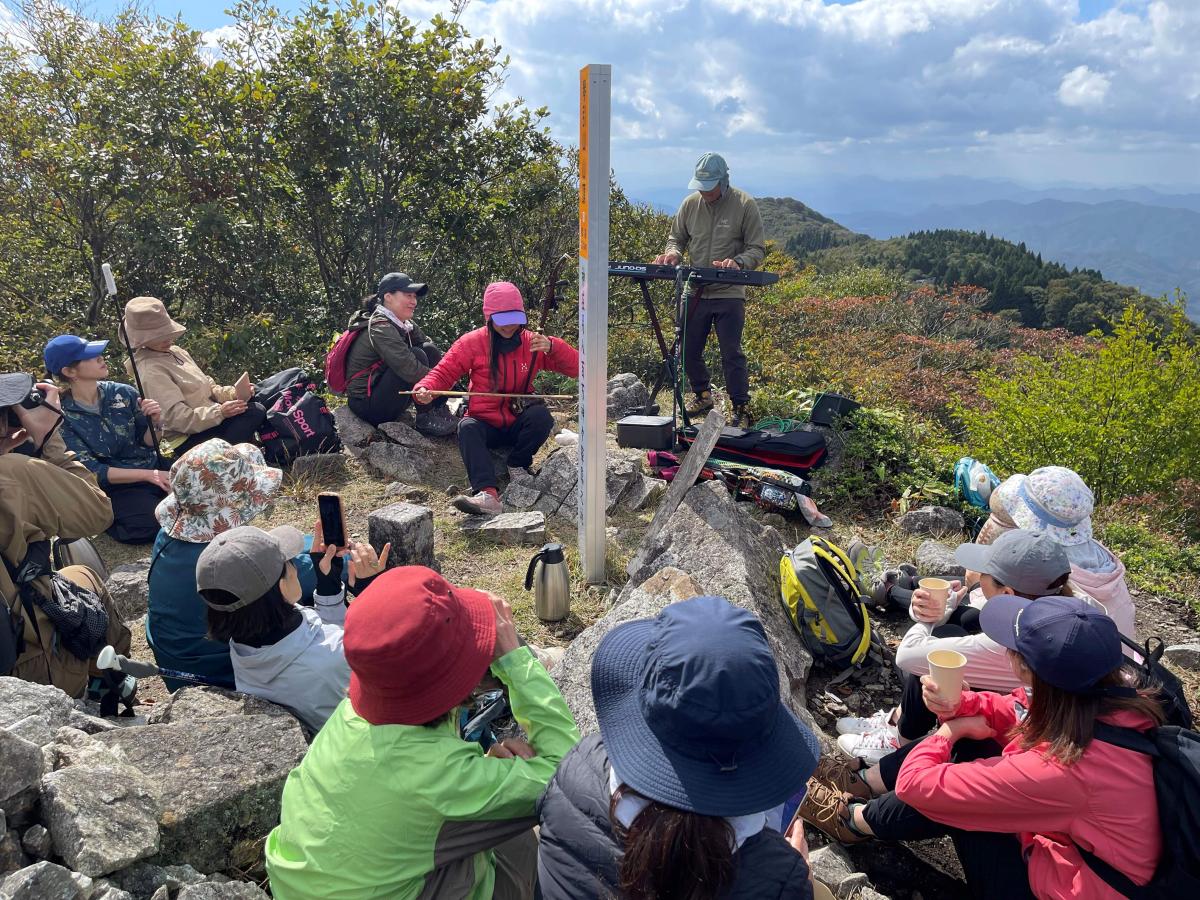 琴引山頂で、コトビキブレンドのコーヒーを片手に、二胡とキーボードの演奏に聞き入る参加者たち