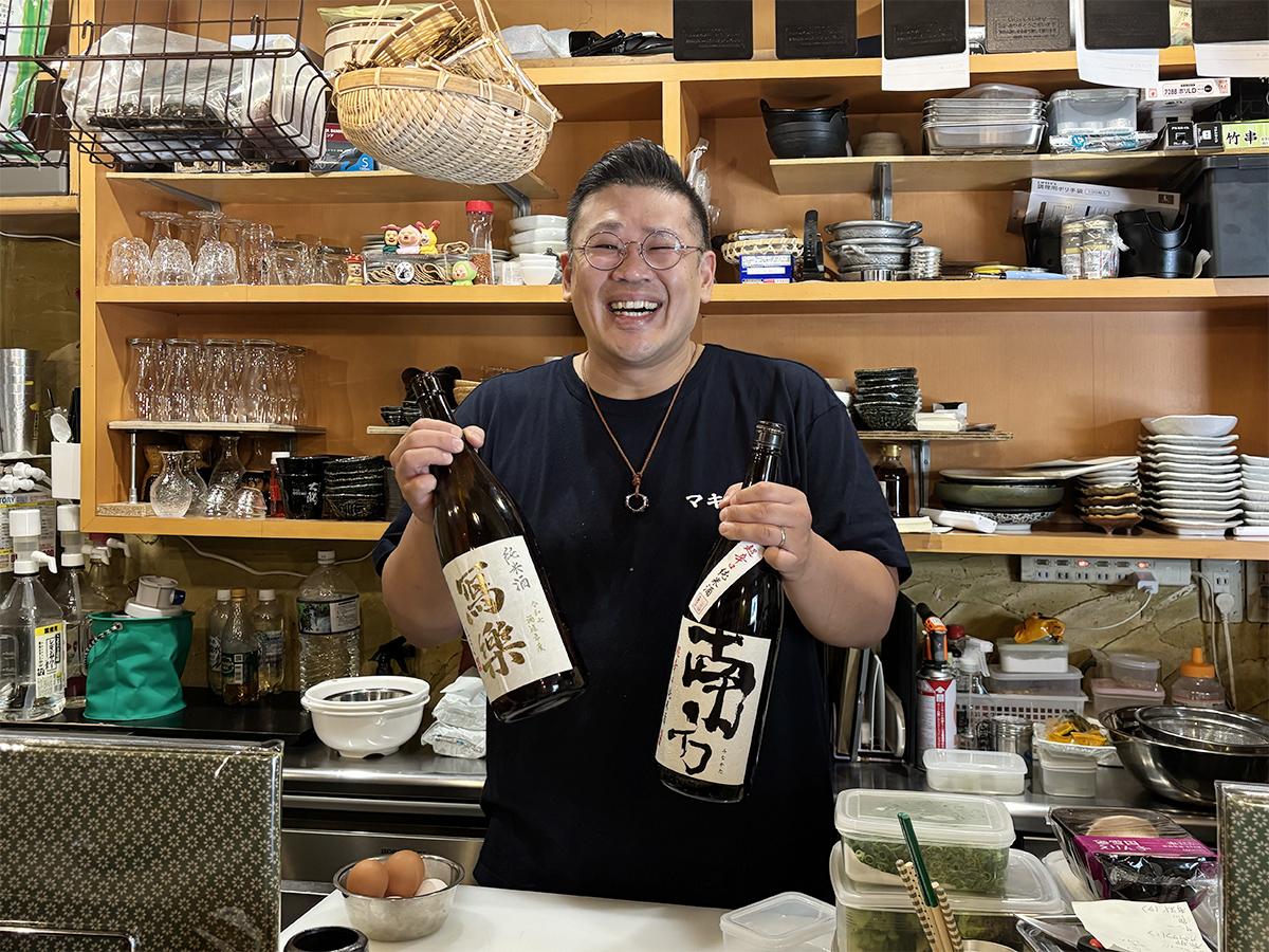 居酒屋「巻ト酒 マキチヨ」でお薦めの酒を手にする森下智紀さん