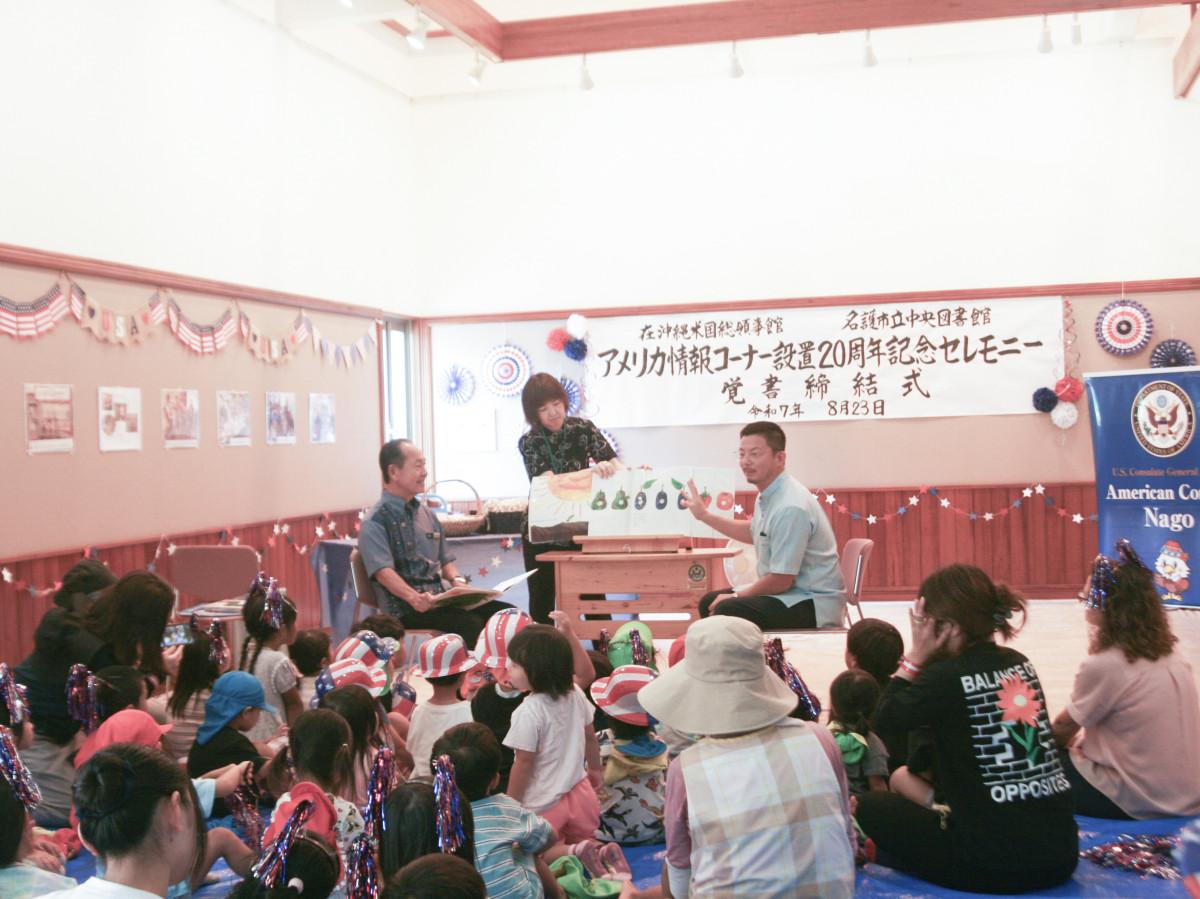 読み聞かせを行う渡具知武豊名護市長と在沖米国総領事アンドリュー・オウさん