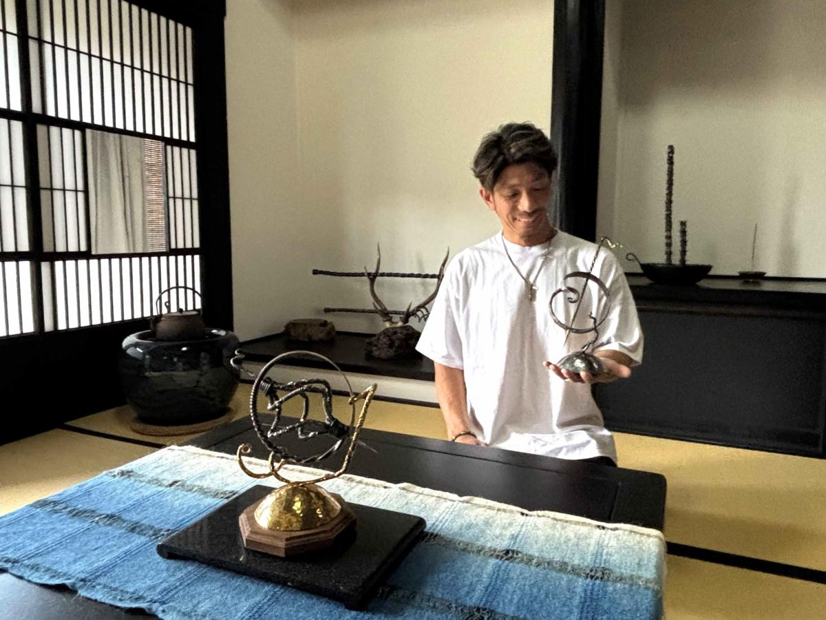 逗子出身の金属造形家・小出隆さん。手前の作品はマスターズ大東京展 日本文化振興会理事長賞受賞作品「波でつながる世界の輪」